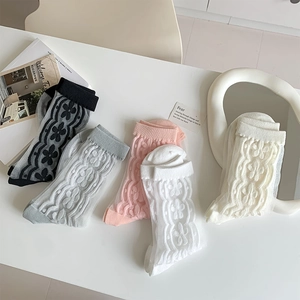 Flat lay of sheer floral crew socks in black, grey, pink, and white on a minimal background