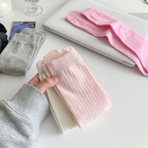 Close-up of ribbed cotton flip-flop socks in multiple pastel colors on a white desk