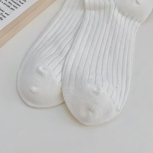 Close-up of white ribbed cotton socks featuring fine vertical stripes and smooth toe seams
