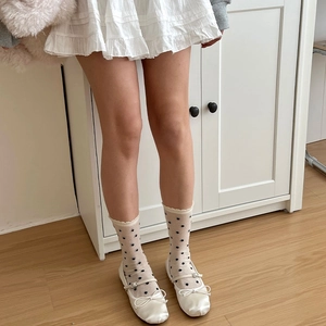 Détail de chaussettes en dentelle crème à pois et chaussures en satin blanc à nœud