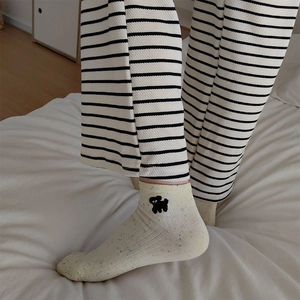 Detailed embroidery of a black puppy on cream cotton socks with rainbow speckled yarn