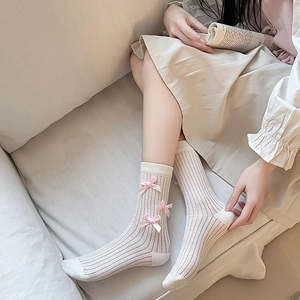 Detail of cream rib-knit knee high socks with pink satin bows in balletcore aesthetic