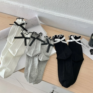 Detail of delicate ribbon bows and ruffled edges on ribbed mesh high socks