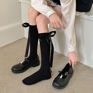 Black over-the-knee socks with satin bows and pearl Mary Jane shoes in preppy style