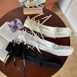 Detailweergave van Lolita-kniekousen met zijden strikken in wit, crème en zwart