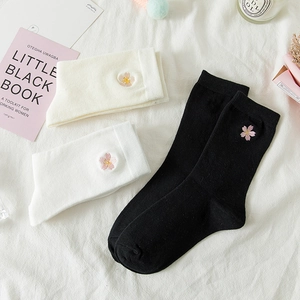 Detailed view of white and black mid-calf socks featuring pink cherry blossom embroidery
