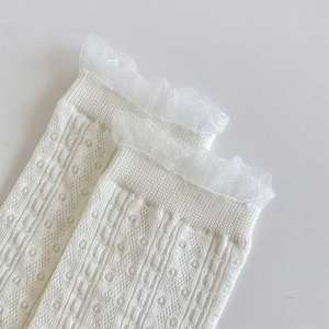 Close-up of white lace ruffle cuffs and hollow knit texture on long Lolita socks