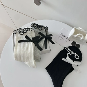 Detailed view of mesh mid-calf socks with lace trim and bows in white grey and black