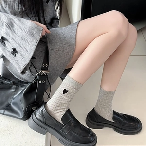 Detailed close-up of grey ribbed crew socks featuring black heart embroidery detail