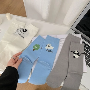 Détail de chaussettes en coton avec broderies de chat, lapin et panda sur fond blanc