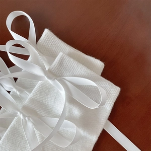 Detailopname van witte geribbelde gebreide sokken met elegante satijnen strik