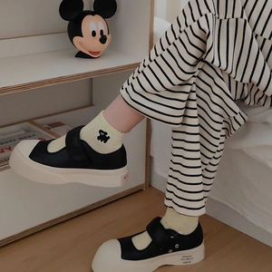 Close-up of Mary Jane sneakers with velcro strap worn with yellow socks in a cozy setting