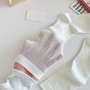 Close-up of white mesh socks showing breathable hollow-out weave and ribbed cuffs