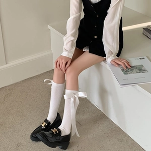 Black patent leather platform loafers with gold buckle and white bow knee-high socks