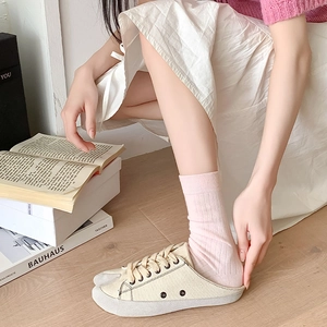 Pink ribbed tabi socks paired with canvas mule sneakers in a cozy home setting