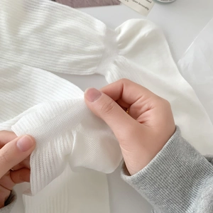 Close-up of white ribbed knit fabric showing high elasticity and breathable mesh structure