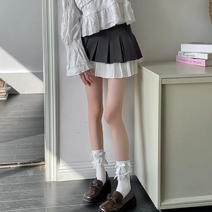 Détail de chaussettes Lolita blanches à nœuds avec chaussures brunes et jupe plissée
