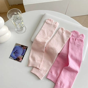 Close-up of pink Tabi socks with vertical ribbed knit texture on a minimalist desk setup
