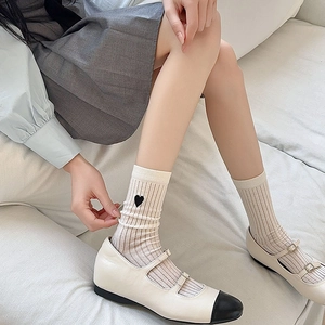 Detail of white ribbed crew socks featuring black heart embroidery and Mary Jane shoes