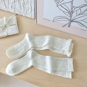 Detail of white Lolita lace socks showing hollow mesh patterns and ruffled cuffs textures