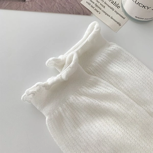 Close-up of white mesh knit socks with elegant ruffle cuffs and soft cotton texture