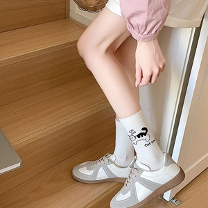 Gros plan de chaussettes mi-hautes avec imprimé chat et baskets classiques en daim