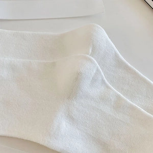 Detailed macro view of white cotton ribbed socks with elegant decorative ribbons