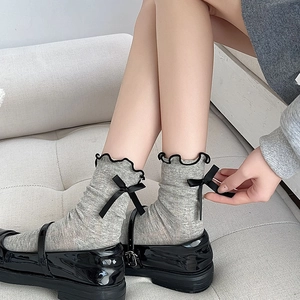 Detail of grey mesh socks with black lace trim and bow knot paired with Mary Janes