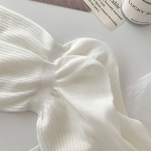 Detail of white ribbed knit fabric with a twist-knot design and soft cotton texture