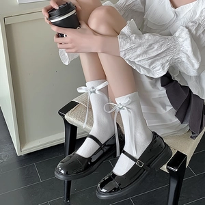 Détail de chaussettes blanches Lolita avec nœuds satinés et charms étoiles argentés