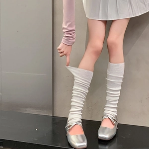 Detail of white ribbed knit leg warmers showing high elasticity and soft texture