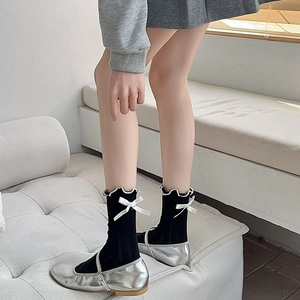 Detail of black knit crew socks with white satin bows and frill cuffs for women
