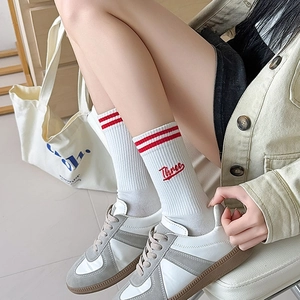 Detail of white cotton ribbed mid-calf socks with red stripes and Three embroidery