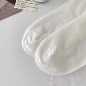 Close-up of white ribbed cotton socks featuring fine texture and smooth toe seam detail