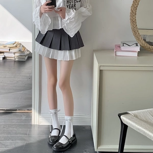 Détail d'une mini-jupe plissée bicolore avec chaussettes à nœuds et chaussures noires