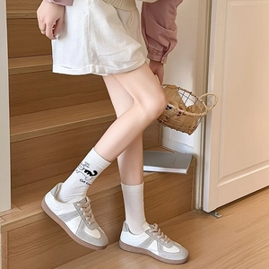 Gros plan de baskets en cuir blanc et taupe avec semelle gomme et chaussettes chat