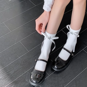 Détail de chaussettes Lolita blanches avec étoiles argentées et nœuds avec chaussures vernies