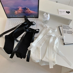 Detail shot of black and white calf socks with large satin ribbons on a desk