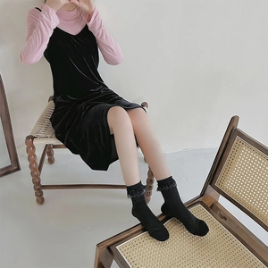 Detail von schwarzen vertikal gestreiften Socken mit Spitzenbesatz und Samtkleid