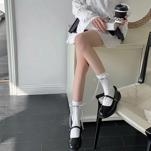 Détail de chaussettes blanches avec nœuds et breloques étoiles et Mary Janes