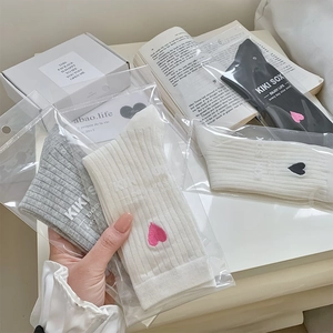 Close-up of ribbed knit socks with heart embroidery in white, grey, and black colors