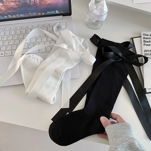 Close-up of stylish knit calf socks featuring elegant large satin bow ribbons in black and white