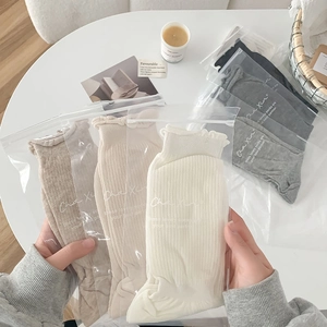 Detail of multi-color ribbed crew socks with lettuce edge cuffs in zipper bag packaging