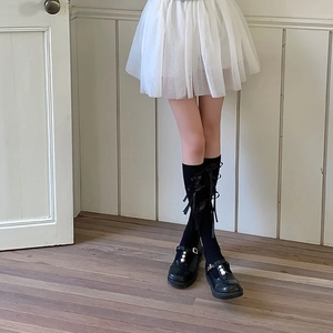 Detail van zwarte kousen met strikken en Mary Jane schoenen met witte parelversiering