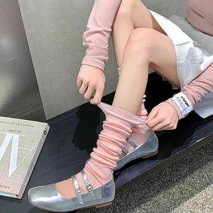 Detail of pink ribbed knit leg warmers with silver Mary Jane shoes and white skirt