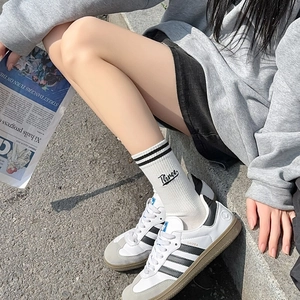 Close-up of white varsity sports socks with double stripes and letter embroidery