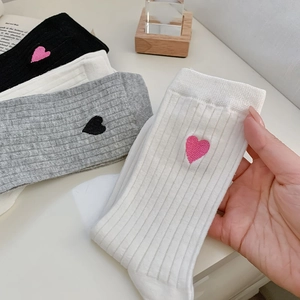 Detail of ribbed cotton socks with delicate heart embroidery in black and white colors