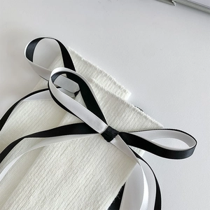 Détail du tricot côtelé blanc avec un nœud en ruban noir et blanc très élégant