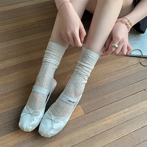 Close-up of white lace hollow mesh knee-high socks with ruffled edges and ballet flats