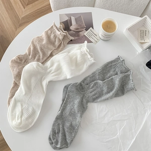 Detail of ruffle cuff cotton socks in beige white and grey with ribbed texture